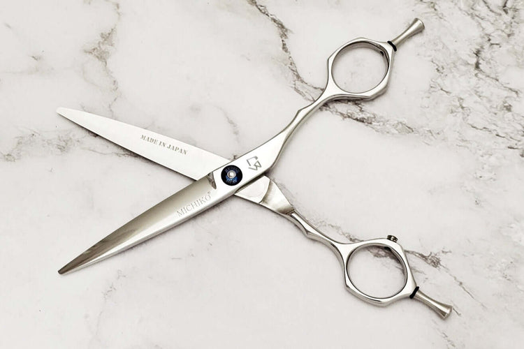 Pair of hair scissors on a marble surface