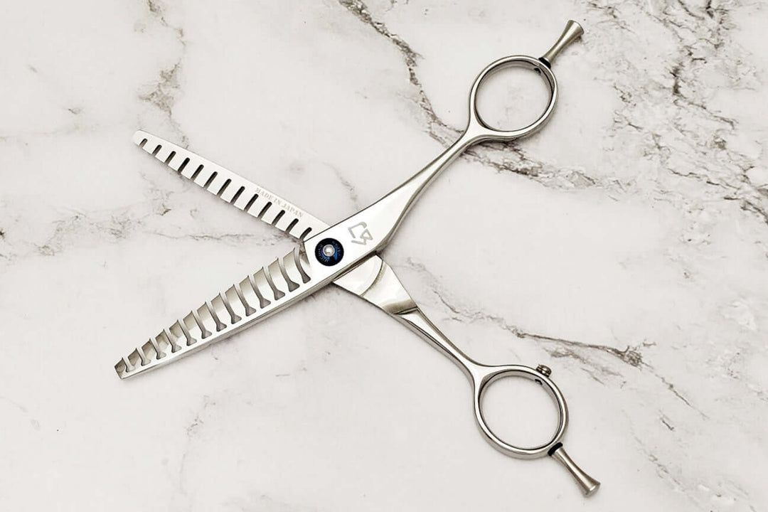 Double teeth hair texturizing shears on a marble surface