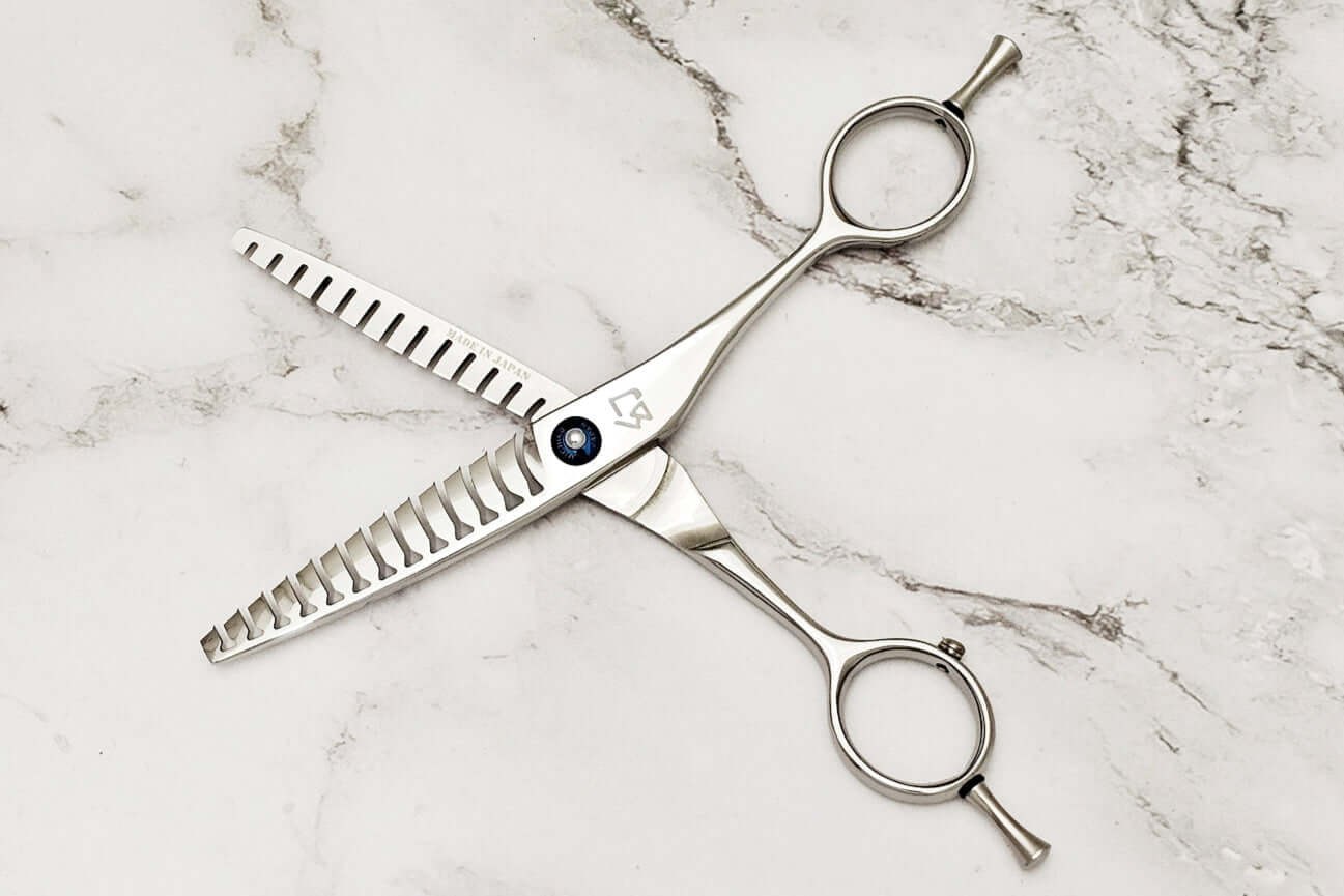 Double teeth hair texturizing shears on a marble surface