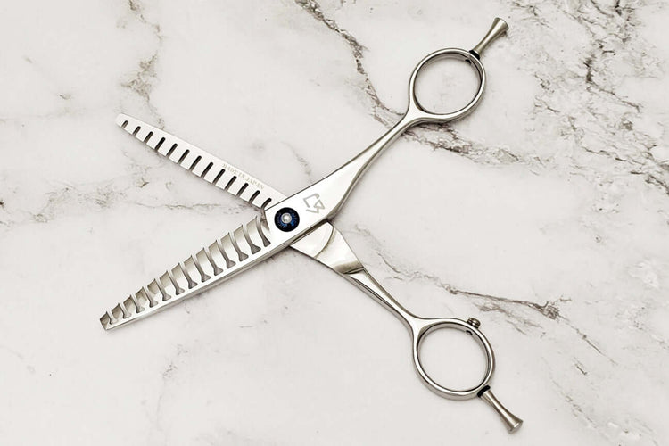Double teeth hair texturizing shears on a marble surface