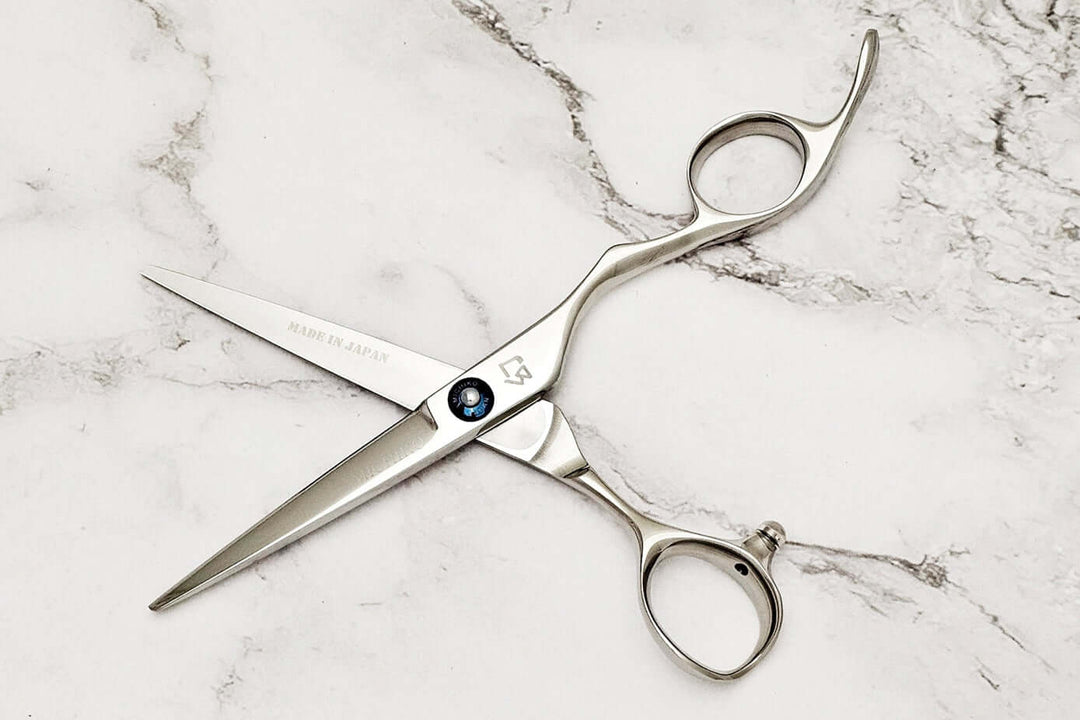 Pair of hair scissors on marble surface