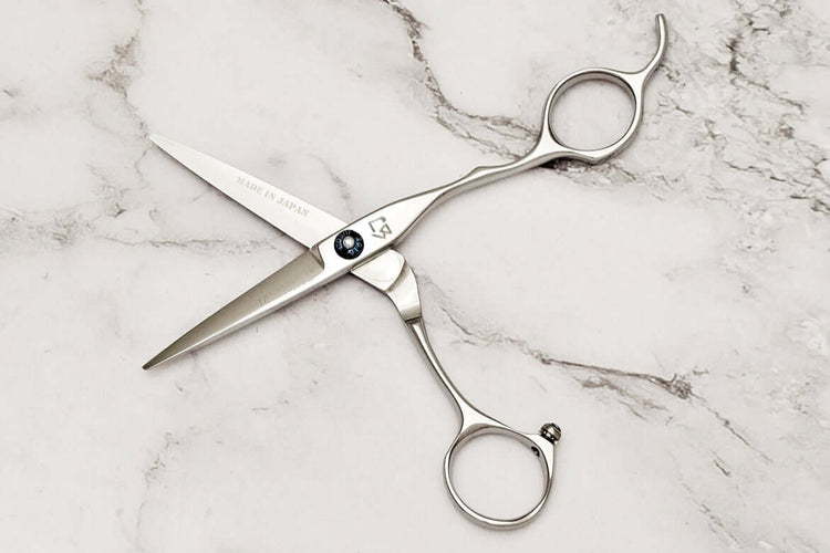 Pair of hair scissors on a marble surface