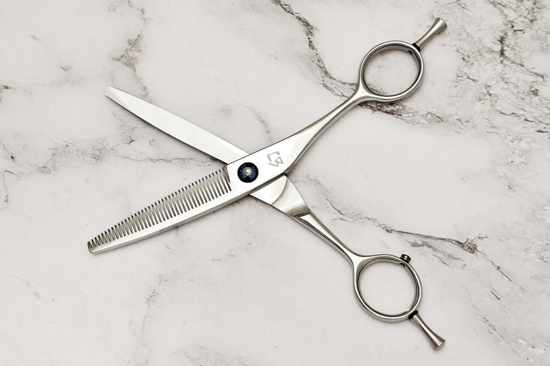 Pair of hair thinning scissors on a marble surface