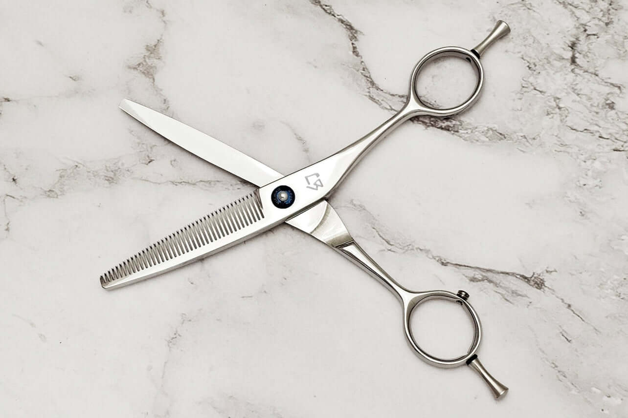 Pair of hair thinning scissors on a marble surface
