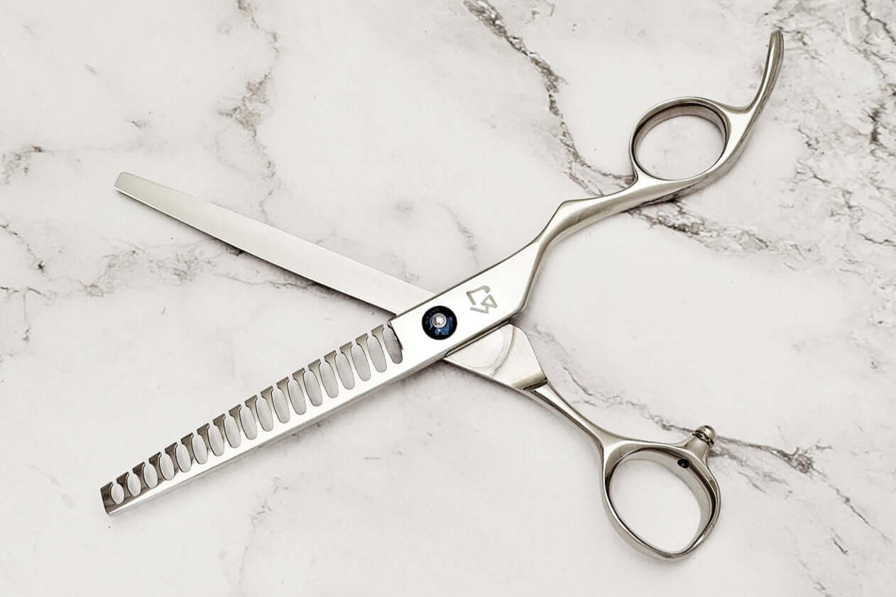 Barber texturizing shears on a marble surface.