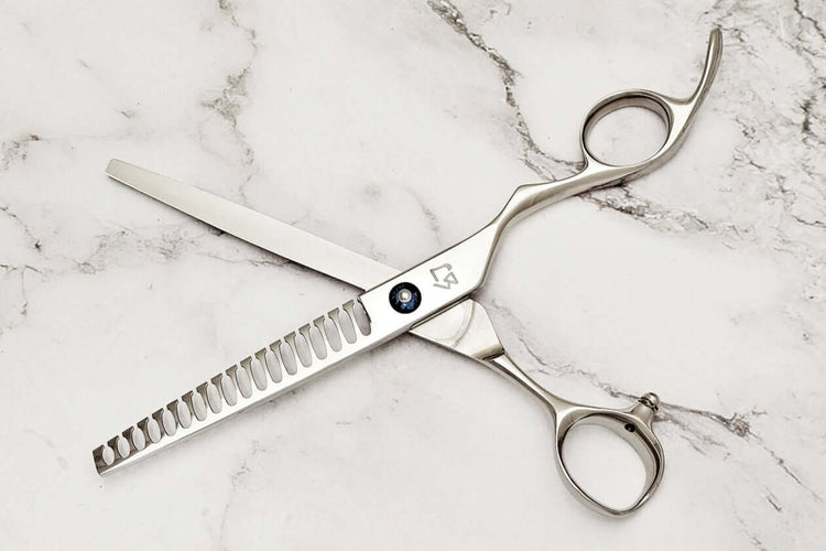 Barber texturizing shears on a marble surface.