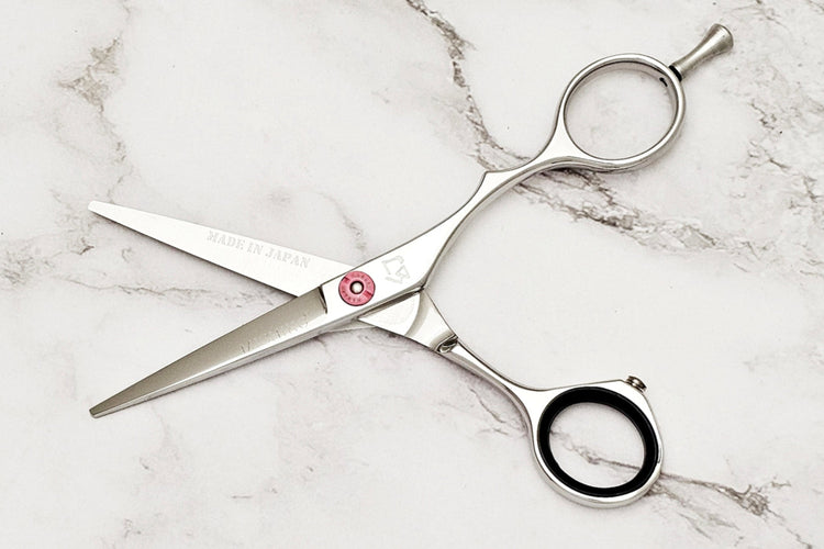 Shrot blade hair scissors on white marble bakcground