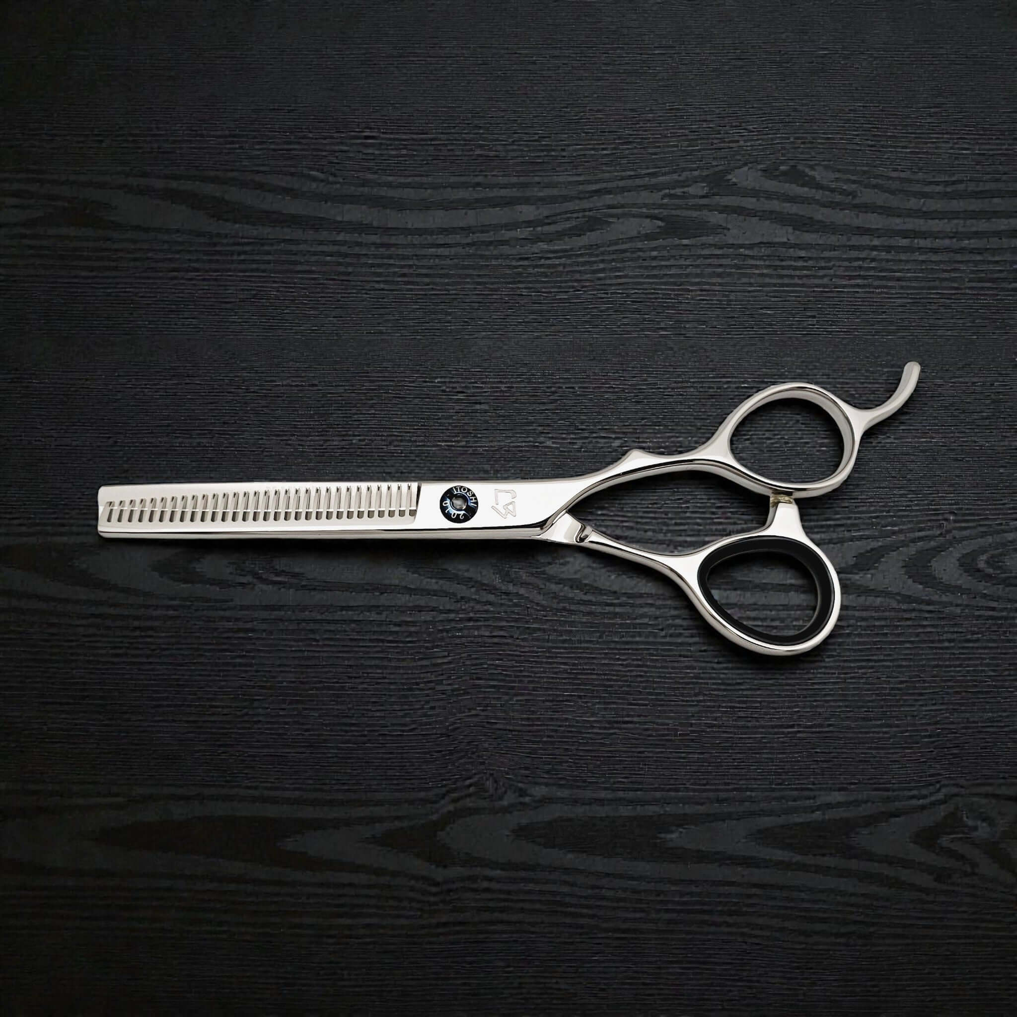 Hair cutting scissors on a black wooden surface