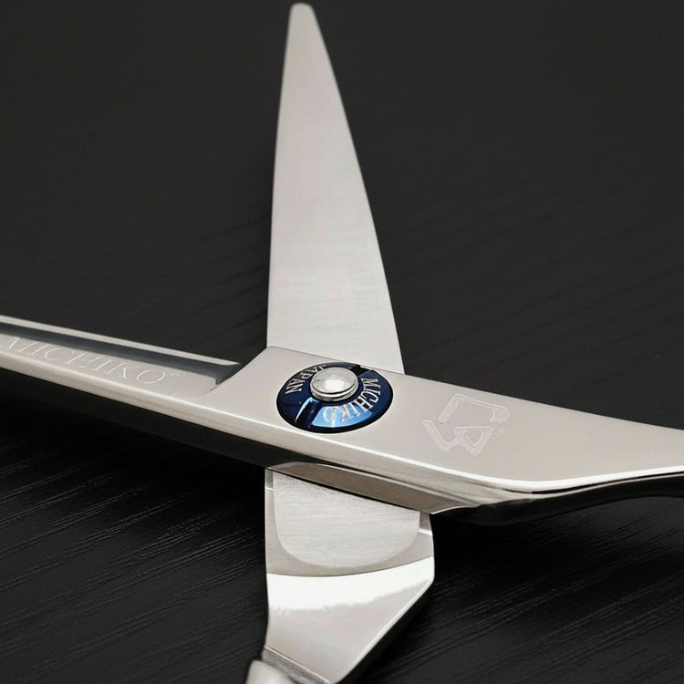 Close-up of a pair of hair scissors with a visible brand logo on a black oak textured background