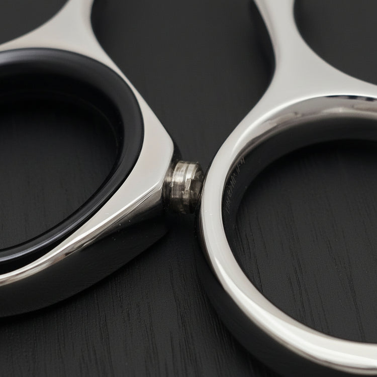 Close-up of finger and thumb rings of hair shears on a black oak textured background