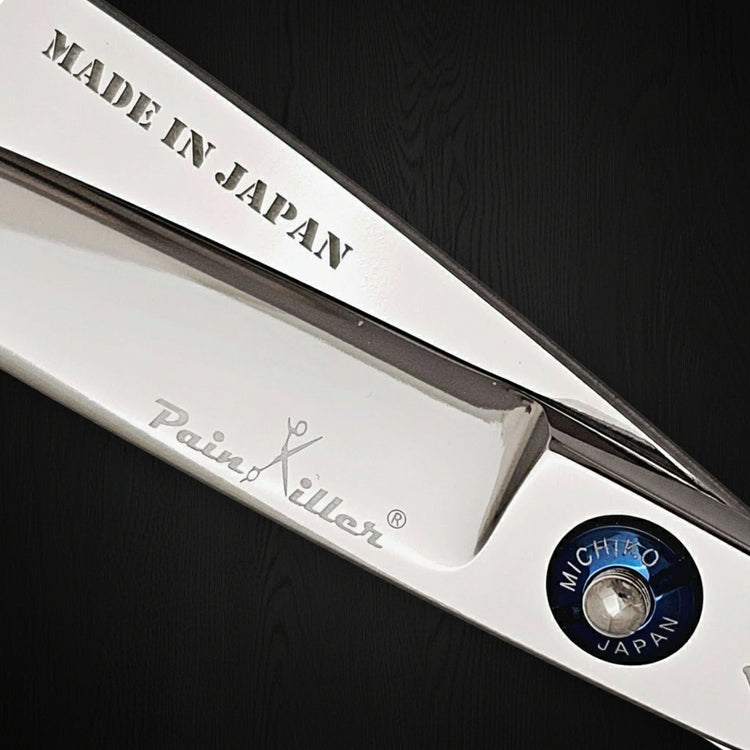 Close-up of a pair of hair scissors with 'Made in Japan' and 'PainKiller' branding on a black background.