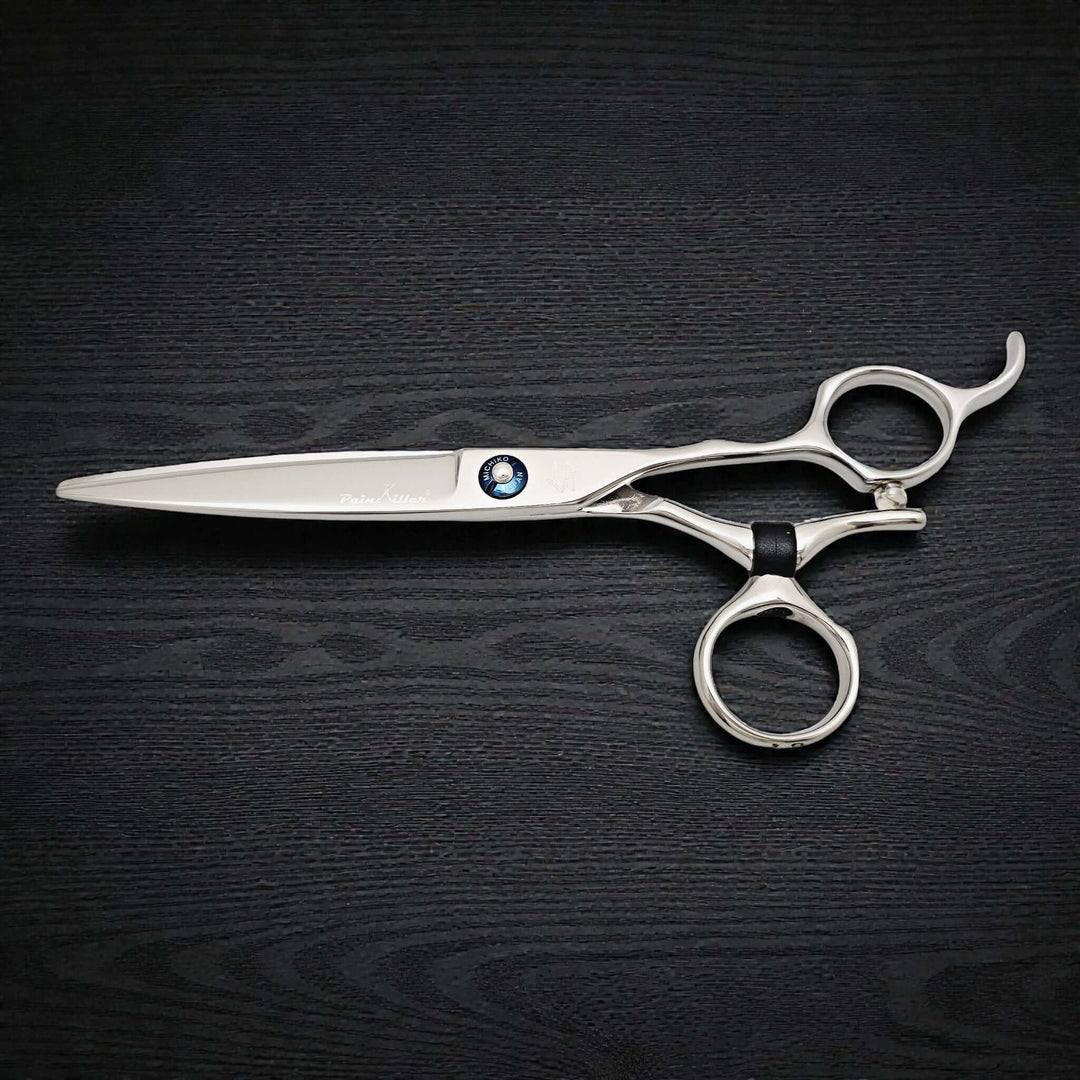 Silver scissors with a black handle on a dark wooden surface