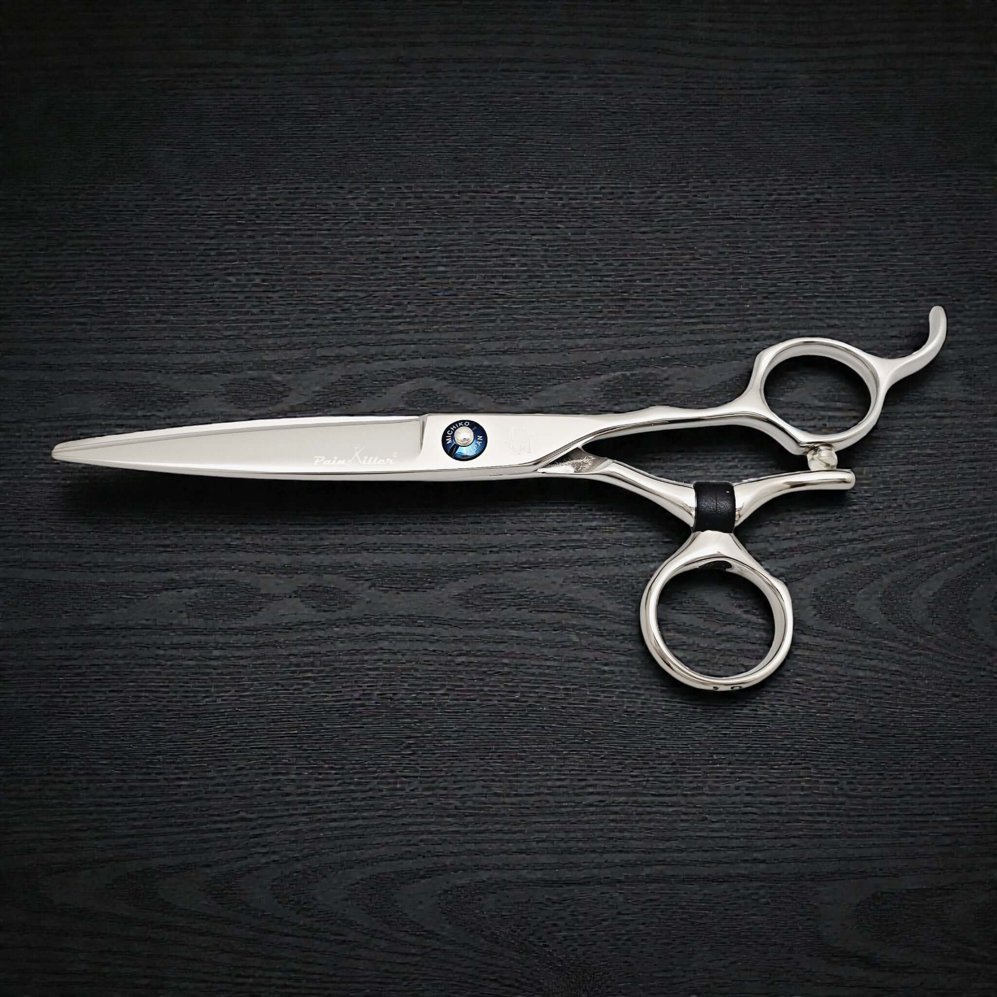 Silver scissors with a black handle on a dark wooden surface