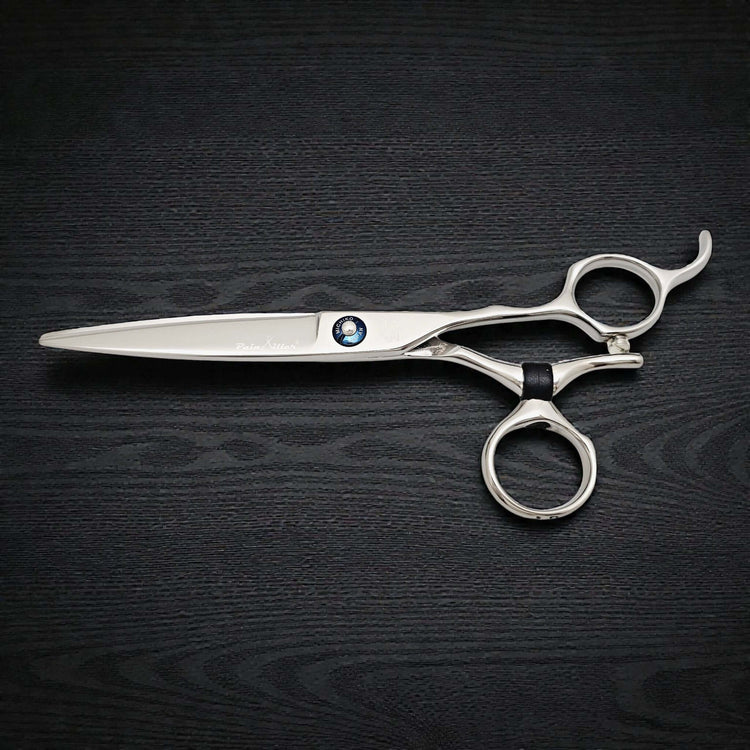 Silver scissors with a black handle on a dark wooden surface