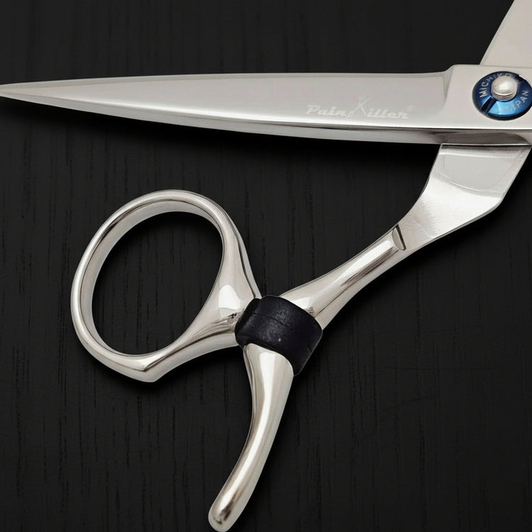 Close-up of a pair of silver swivel hair scissors on a black background