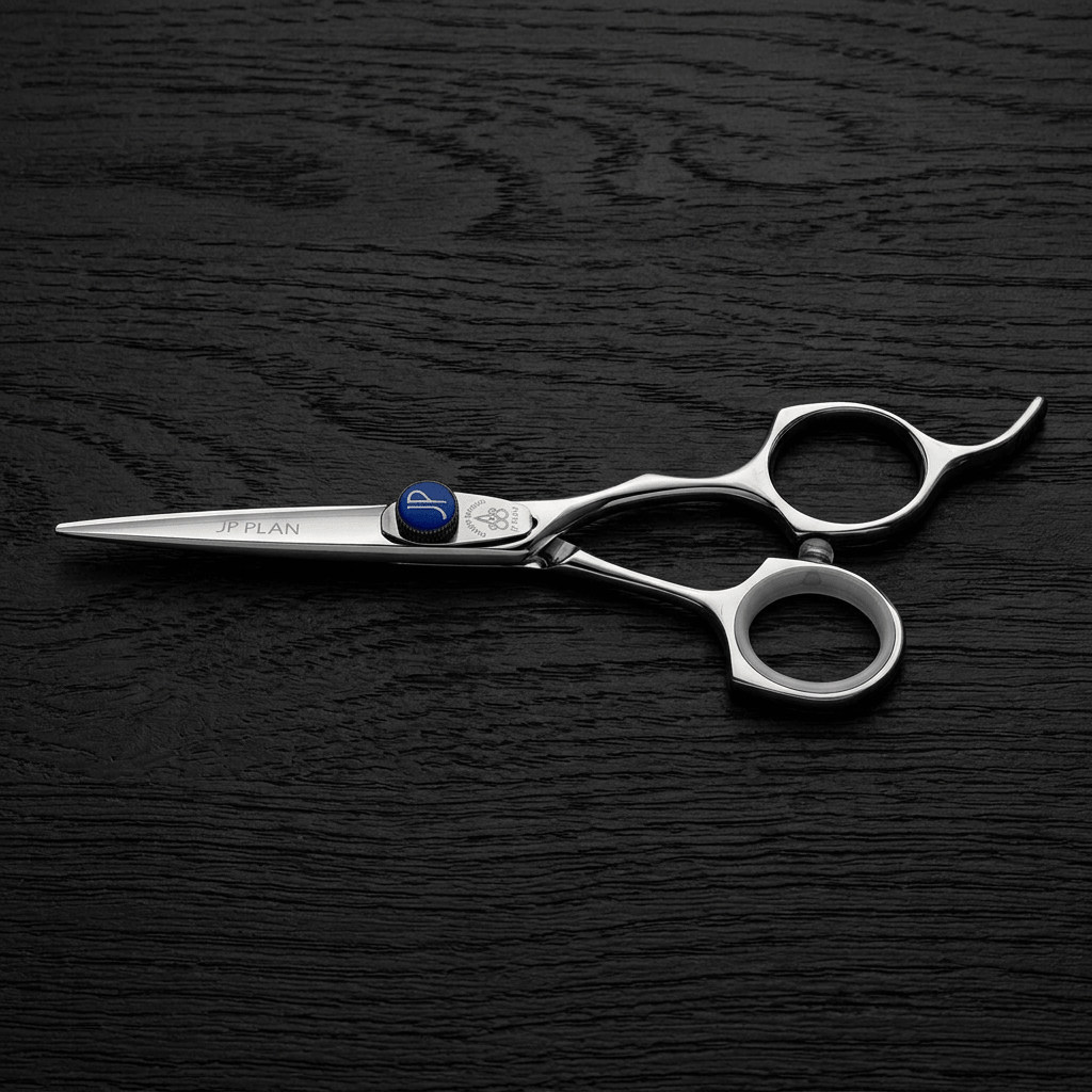 A pair of silver professional hair shears with a small blue accent screw, displayed diagonally on a dark wood-textured background.
