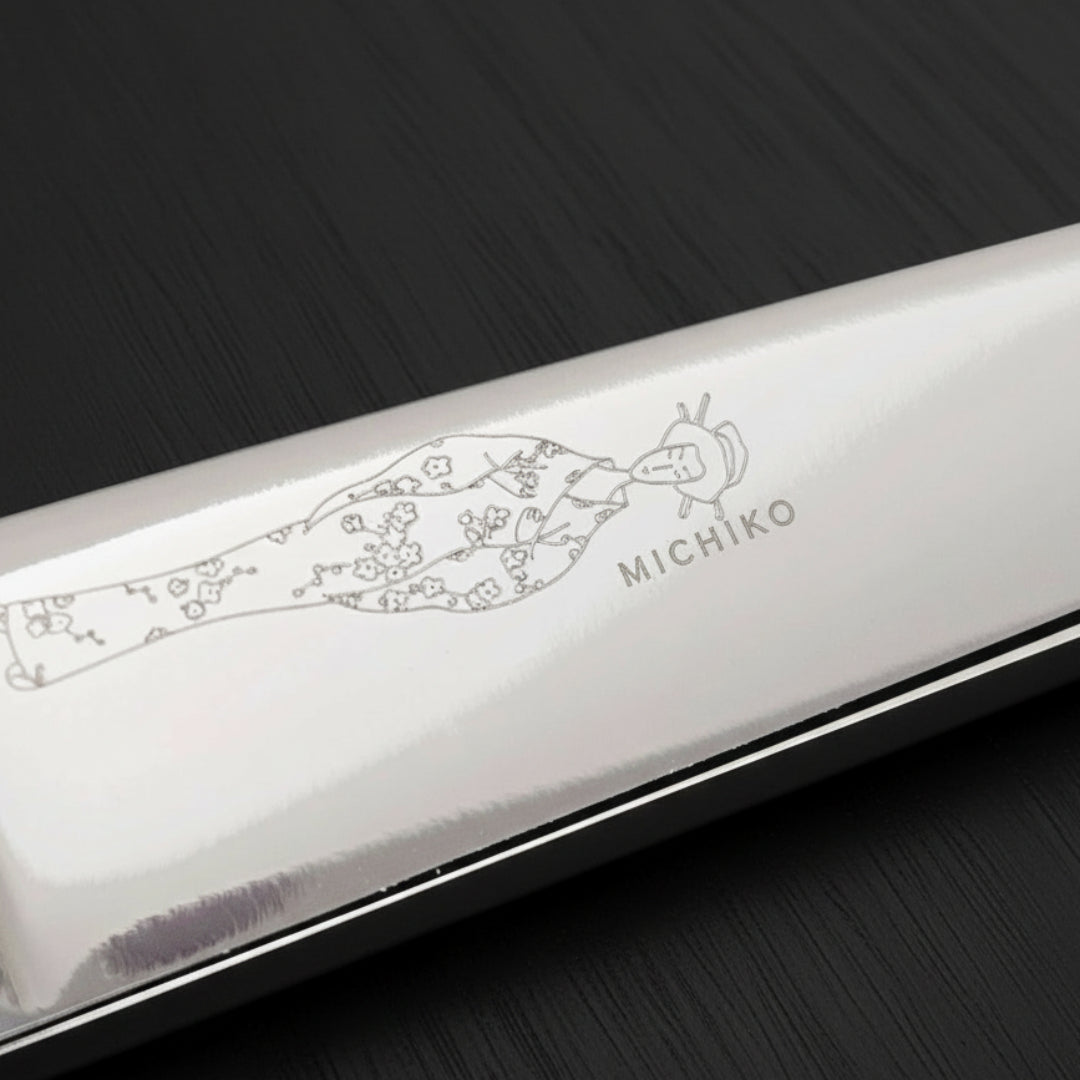 Silver hair scissor blade with an engraved Japanese lady wearing a kimono design on a black oak textured background