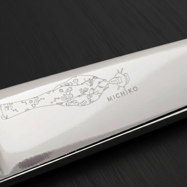 Silver hair scissor blade with an engraved Japanese lady wearing a kimono design on a black oak textured background