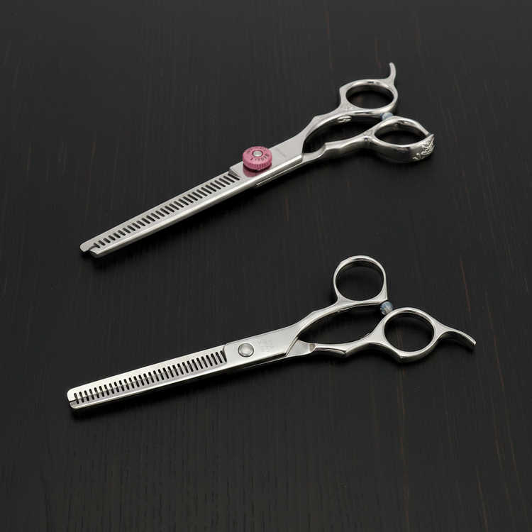 Two pairs of silver thinning scissors on a dark wooden surface, showing the front and back of the shears.