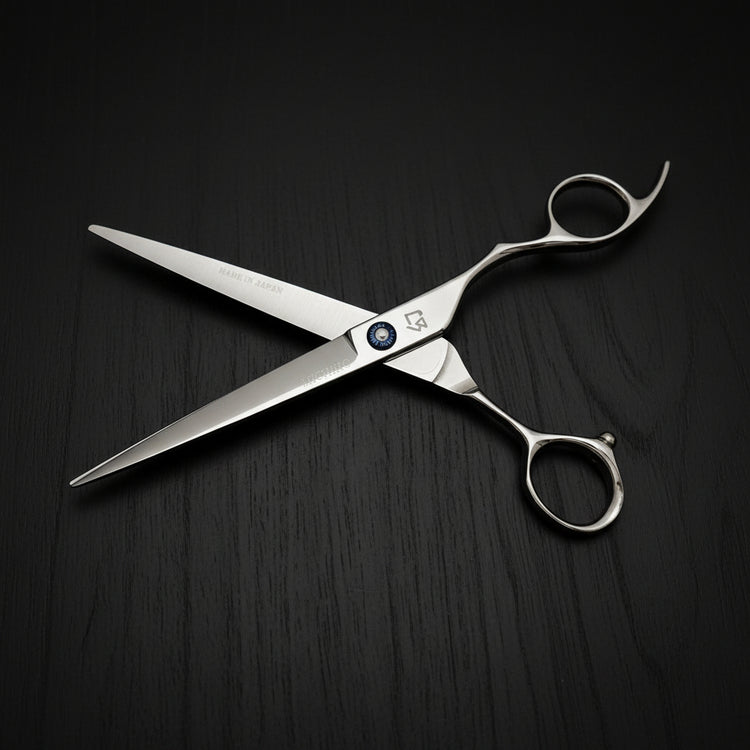 Hair-cutting scissors with a brand logo on a black oak textured background