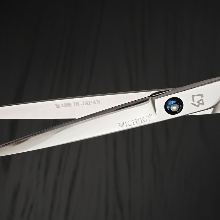 Hair shears with 'MICHIKO' branding on a black oak textured background