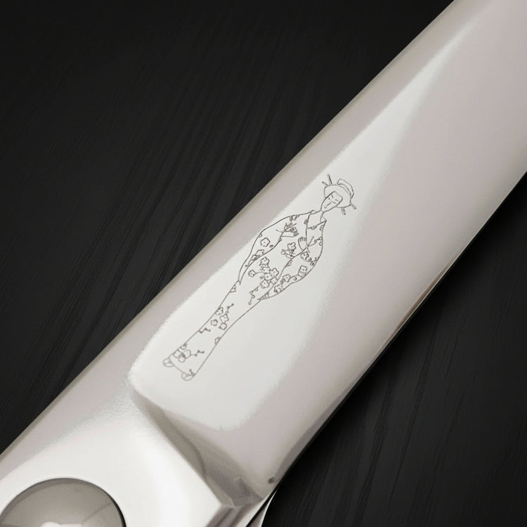 Close-up of a hair scissor blade with an engraved Japanese lady wearing a kimono design on a black oak textured background