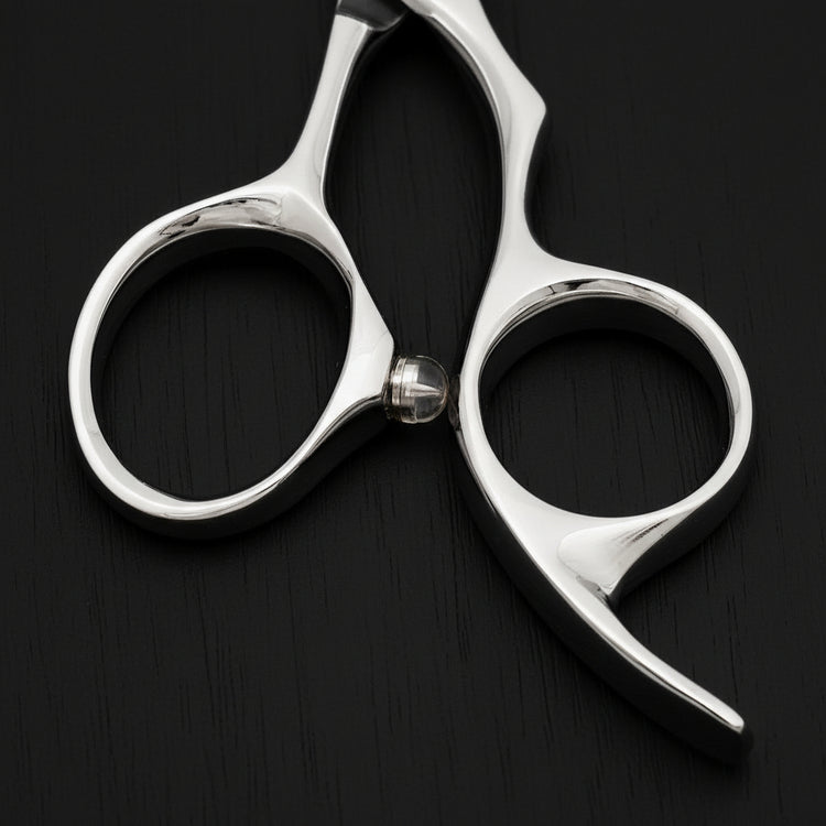 Close-up of a pair of hair scissors on a black oak textured background