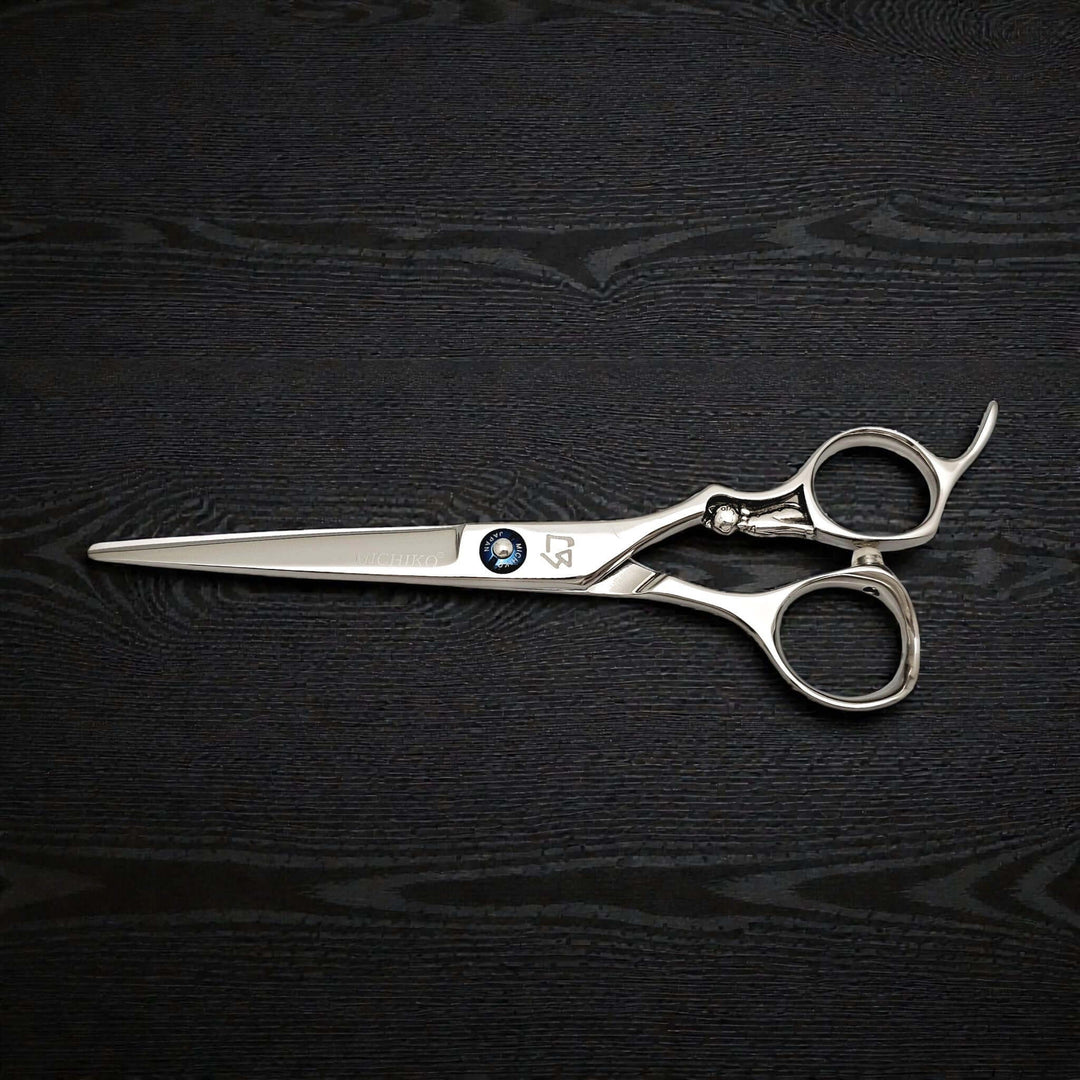 Pair of silver scissors on a black textured surface