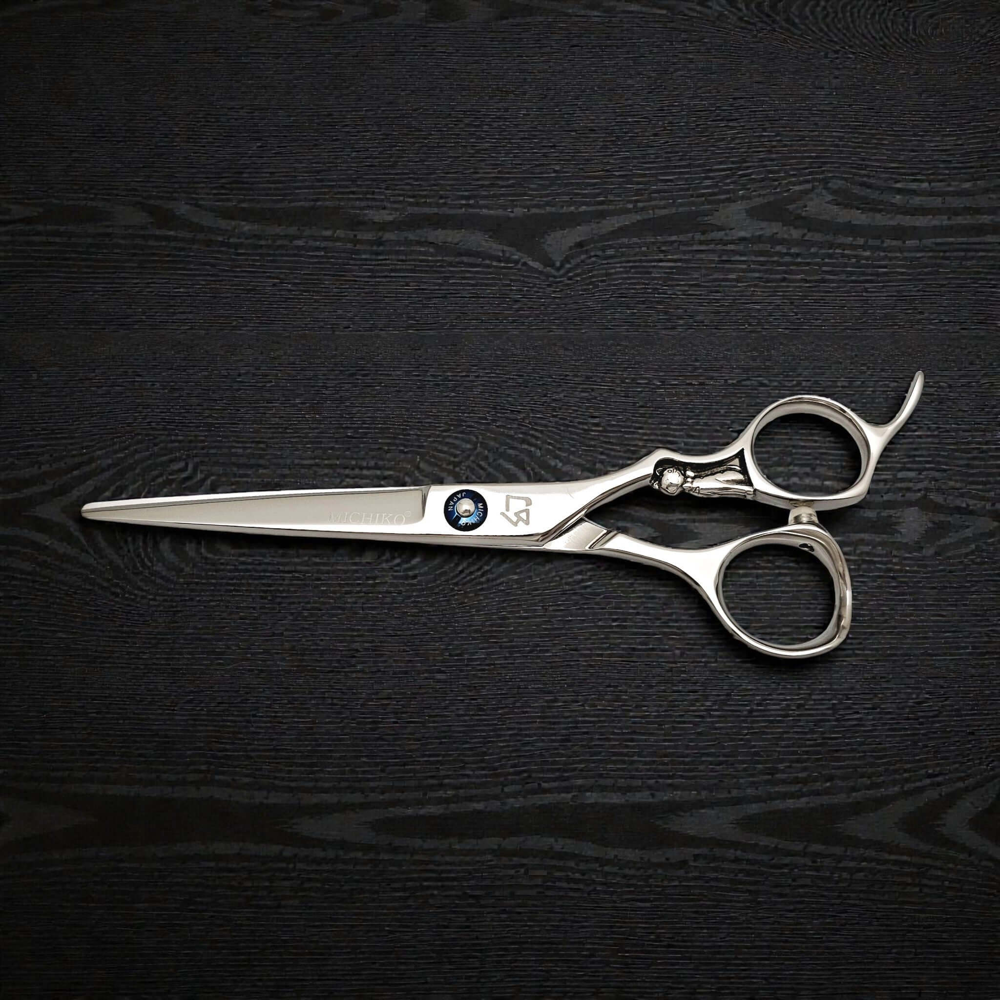 Pair of silver scissors on a black textured surface