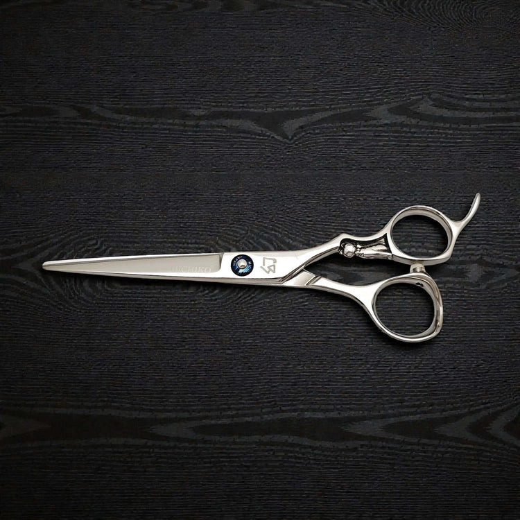 Pair of silver scissors on a black textured surface