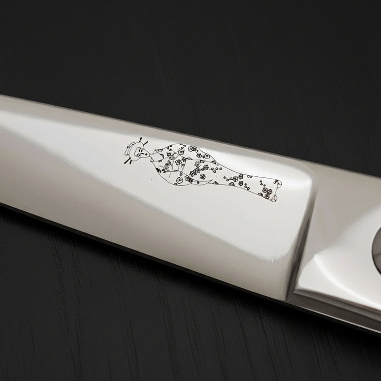 Close-up of a hair scissor blade with an engraved Japanese lady wearing a kimono design on a black oak textured background