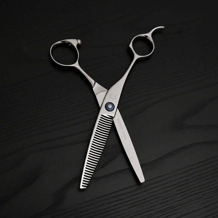 Pair of silver scissors on a textured black surface