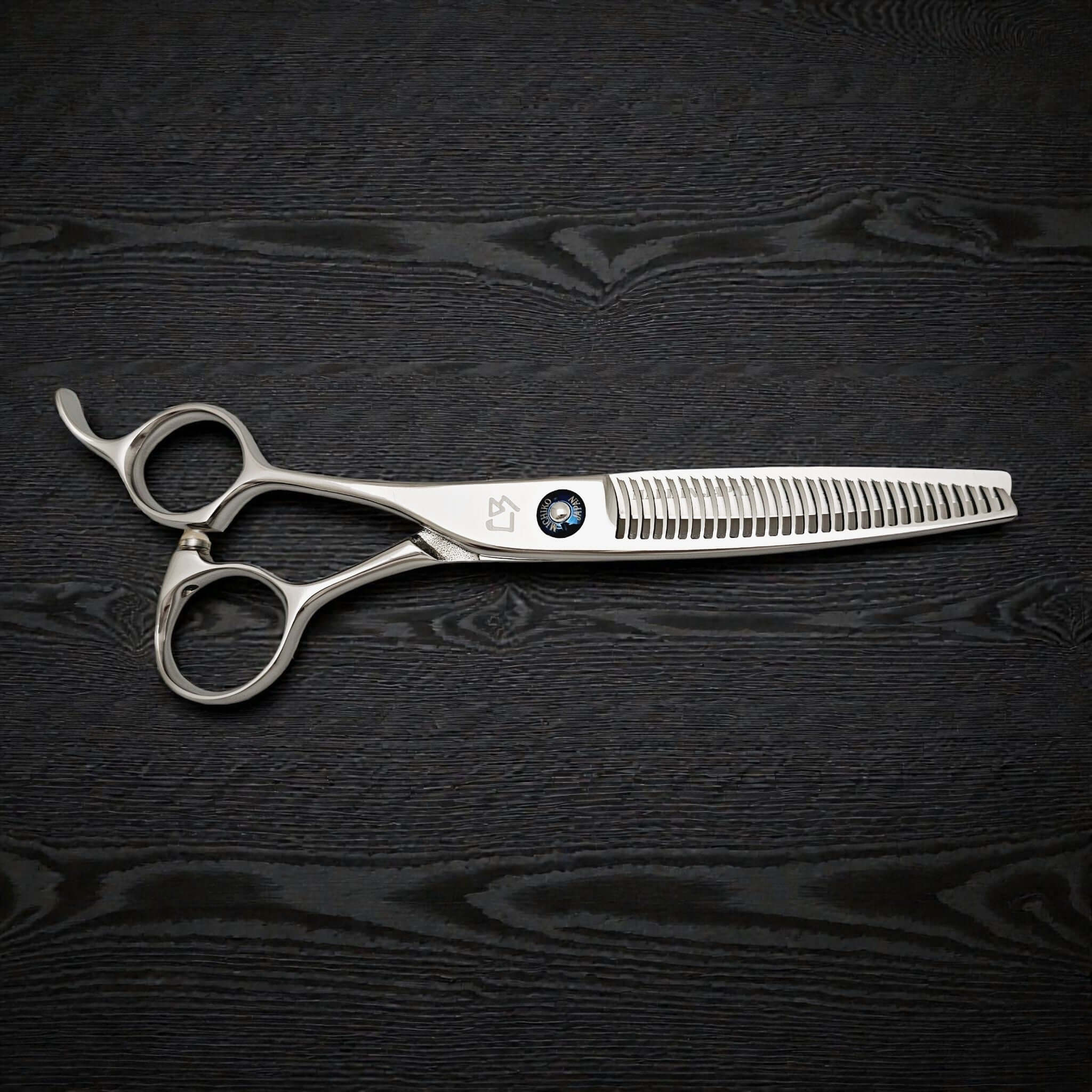 Hairdressing scissors on a black textured surface