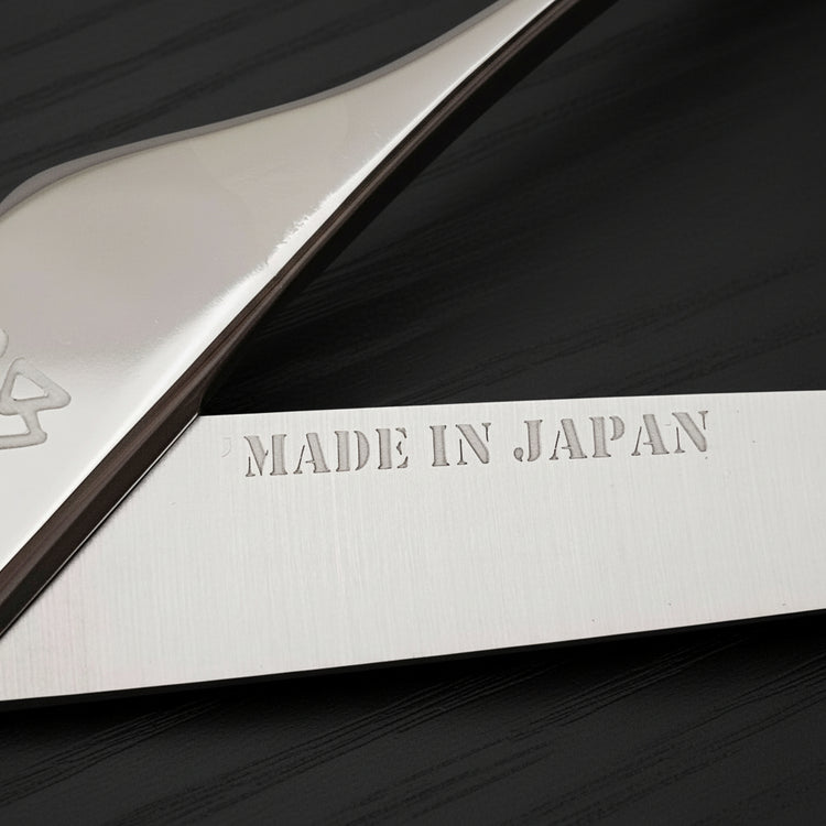 Hair scissors blade with 'MADE IN JAPAN' engraving on a black oak textured background