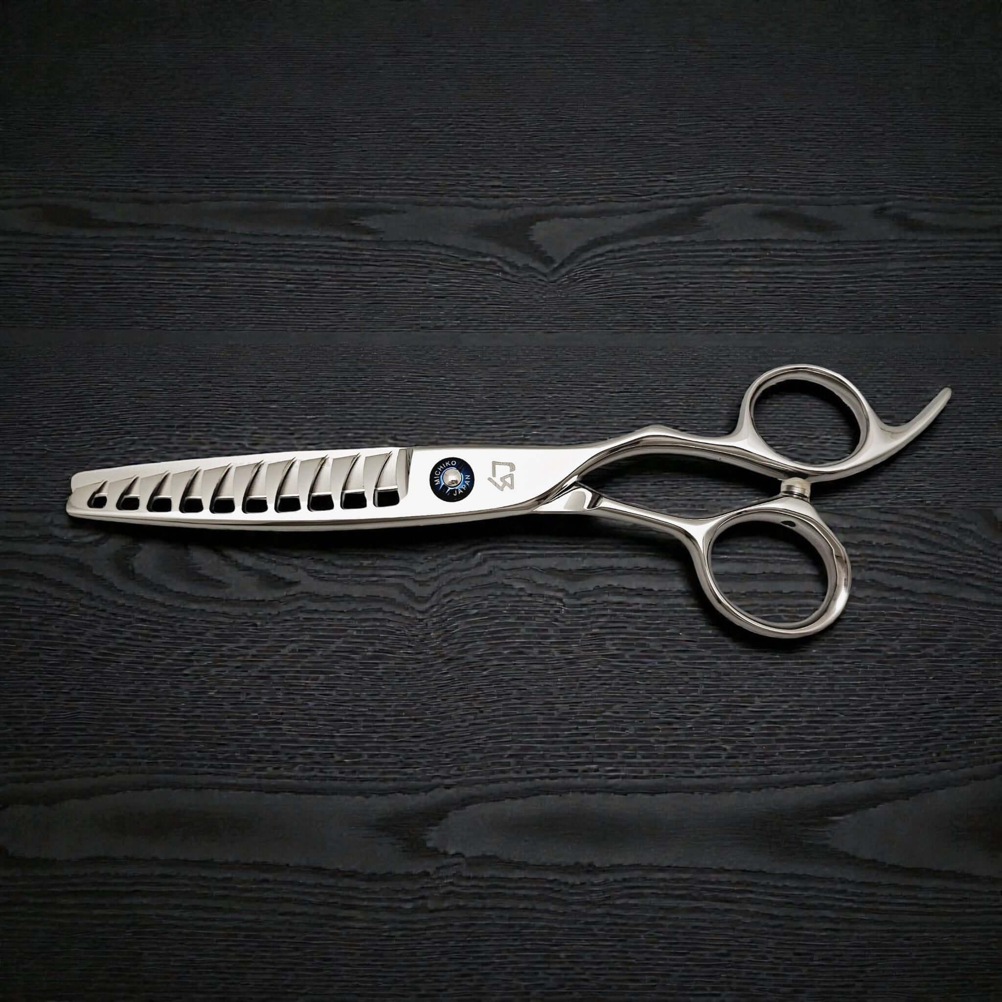 Silver hairdressing scissors on a black textured background