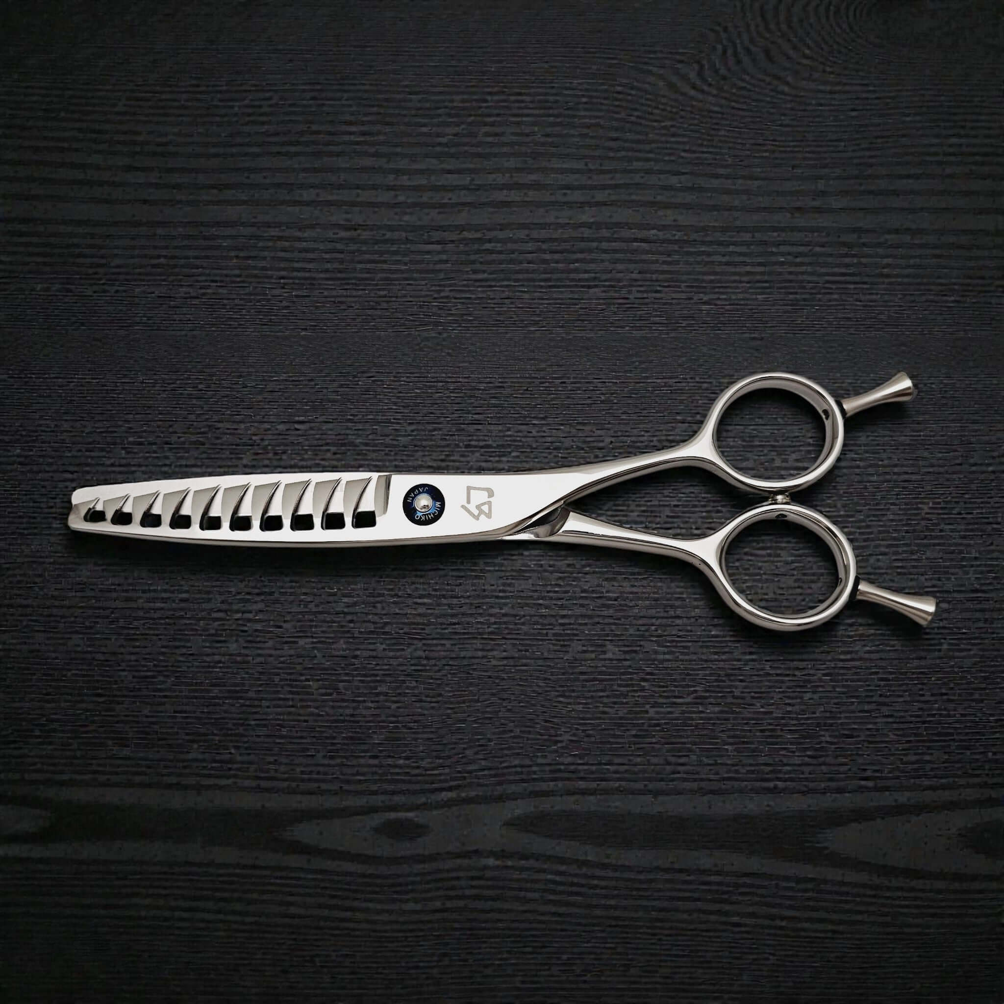 Hair cutting scissors on a black textured surface
