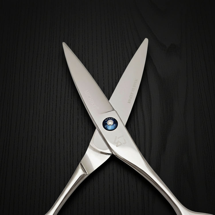 Pair of silver barber scissors on a black background
