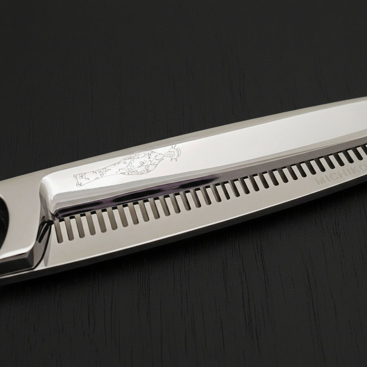 Close-up of hair thinning shears with an engraved Japanese lady design on a black background