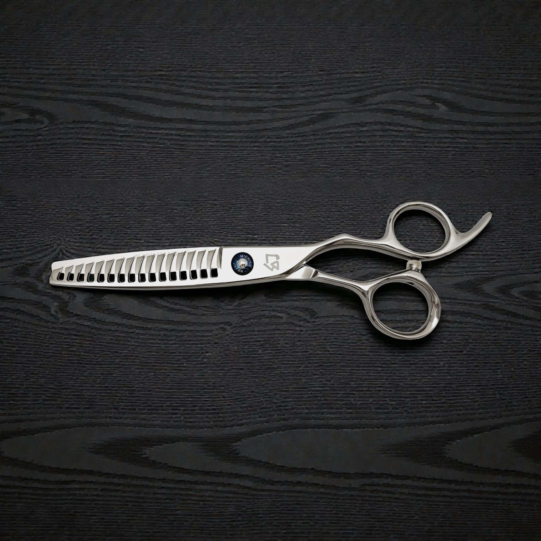Silver hair cutting scissors on a black wooden surface