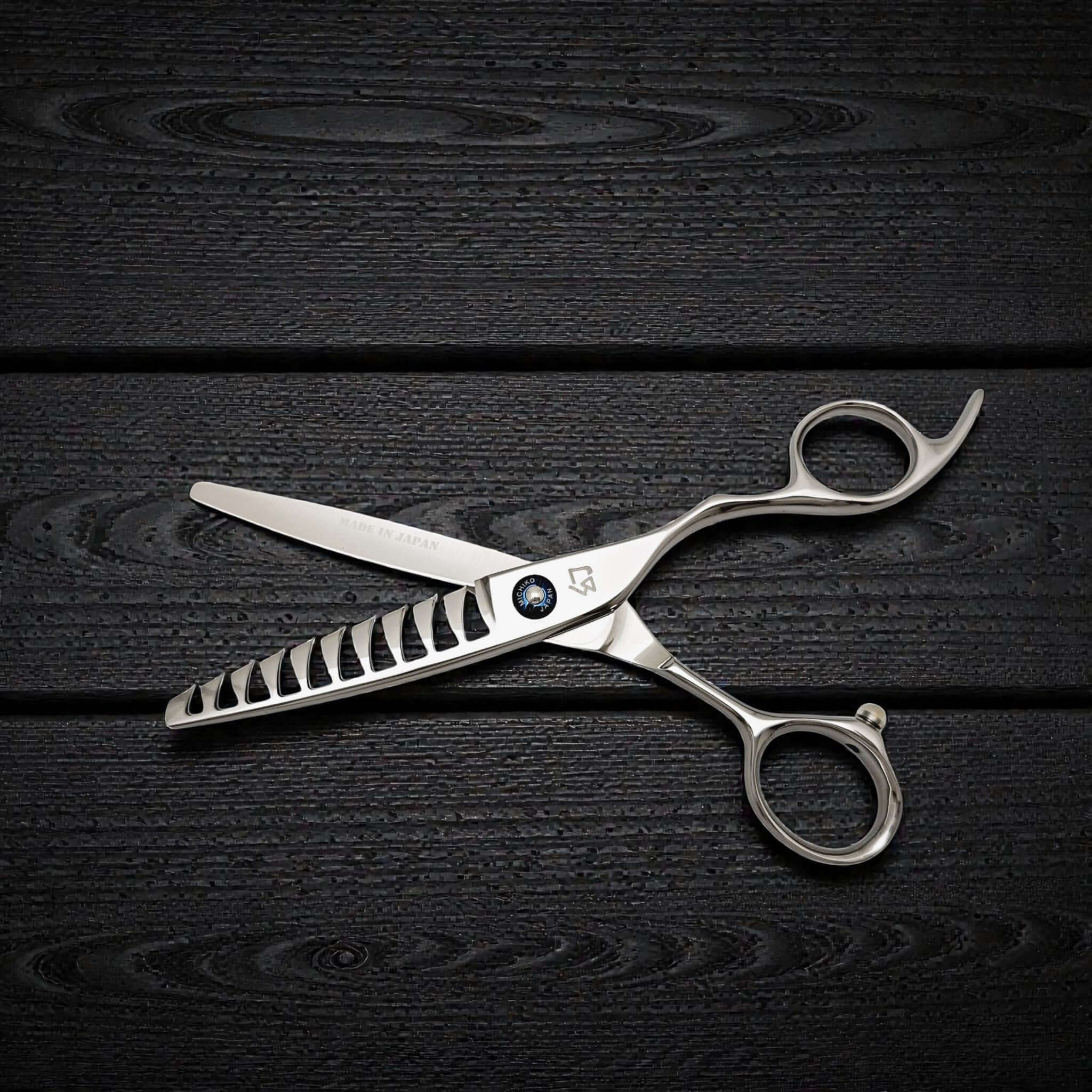 Stainless steel hair cutting shears on a dark wooden surface