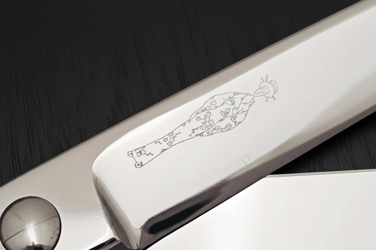 Close-up of hair scissors blade with an engraved Japanese lady design on a dark background