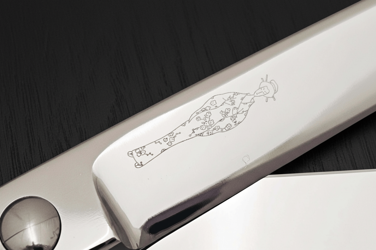 Close-up of hair scissors blade with an engraved Japanese lady design on a dark background