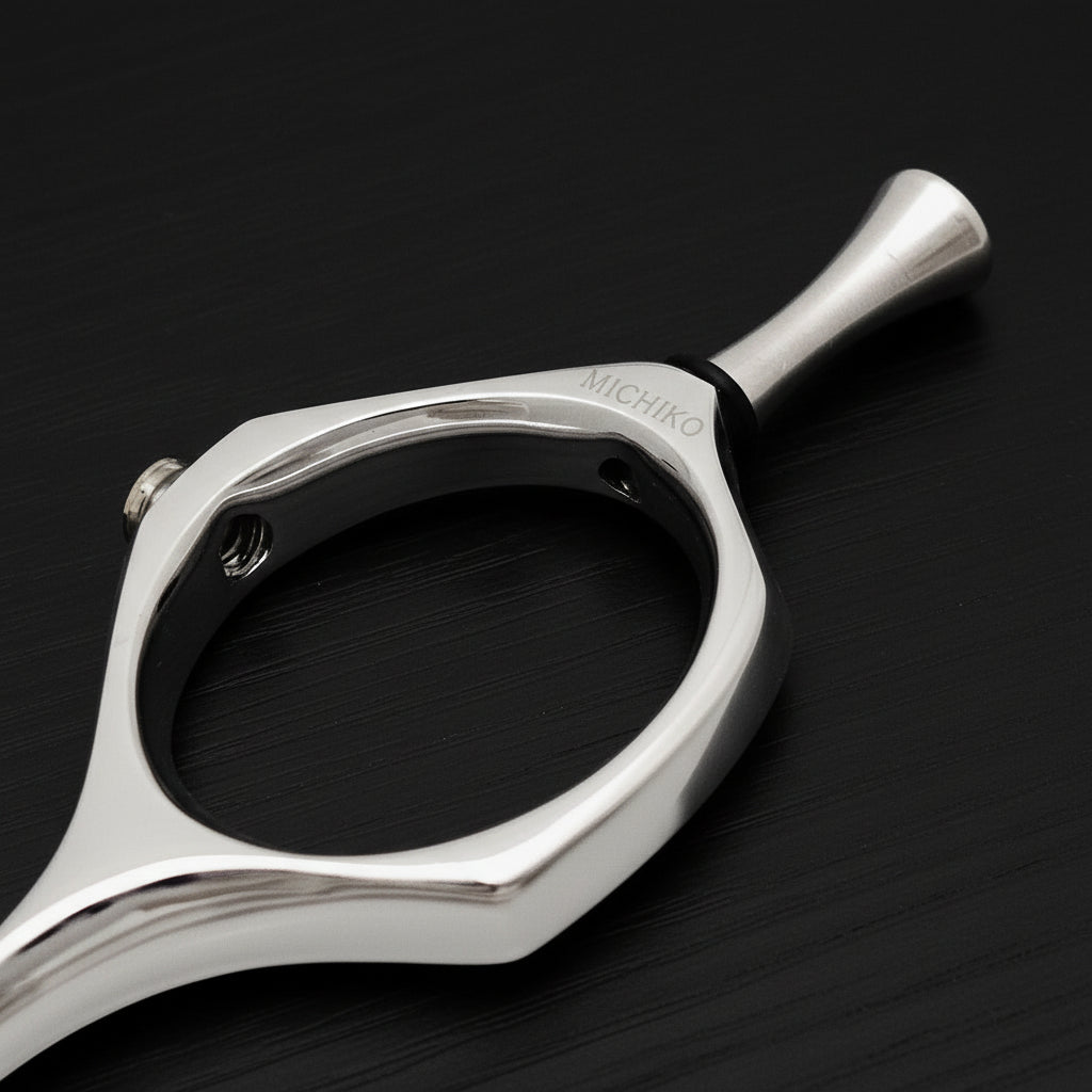 Close-up of a silver hairdressing shear finger ring on a black background