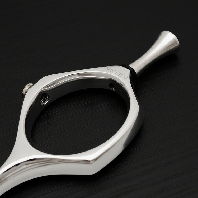 Close-up of a silver hairdressing shear finger ring on a black background
