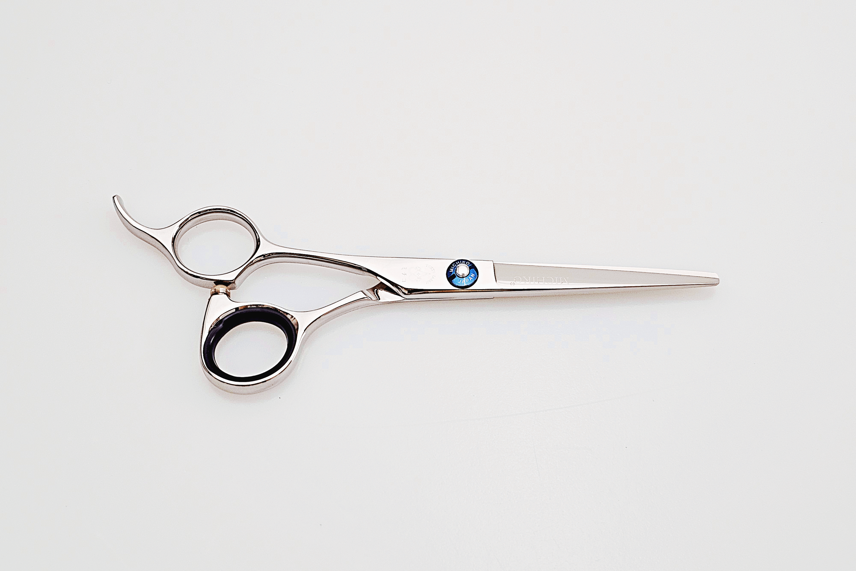 Left handed hair cutting scissors with a brand logo on a white background