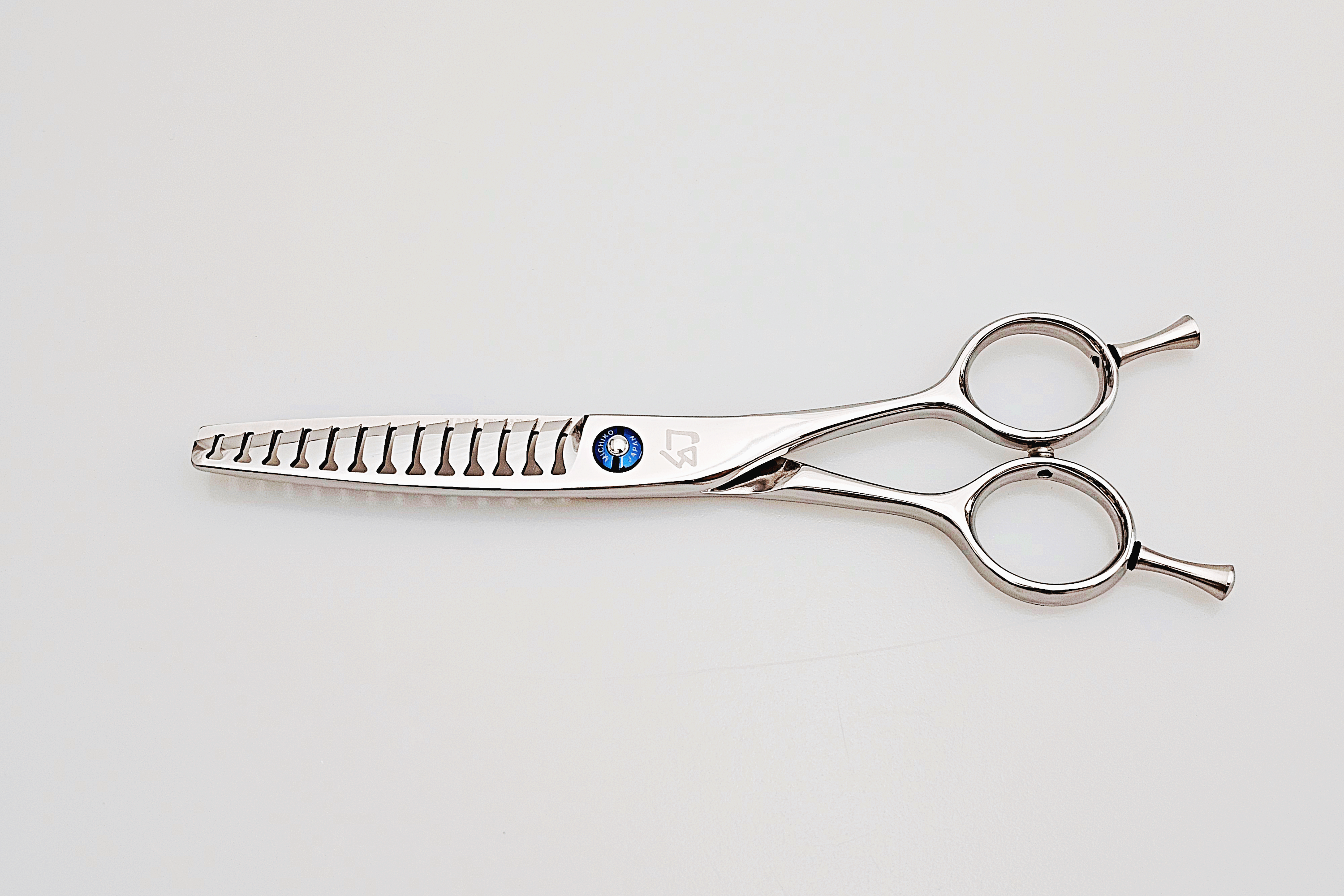 Stainless steel hair cutting shears on a light gray background