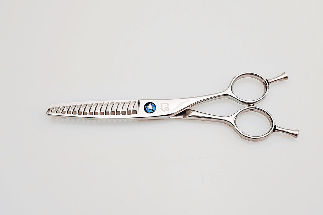 Hair cutting scissors with a blue gemstone on a light gray background
