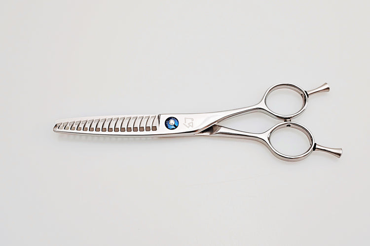 Hair cutting scissors with a blue gemstone on a light gray background