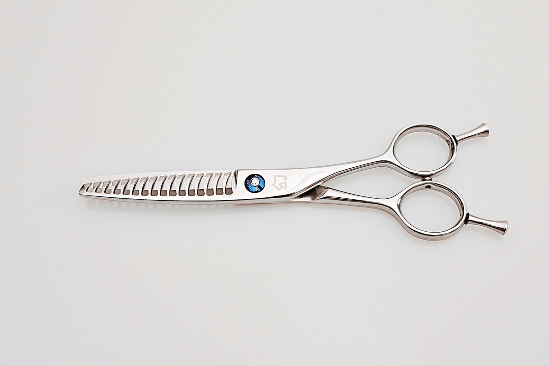 Hair cutting scissors with a blue gemstone on a light gray background