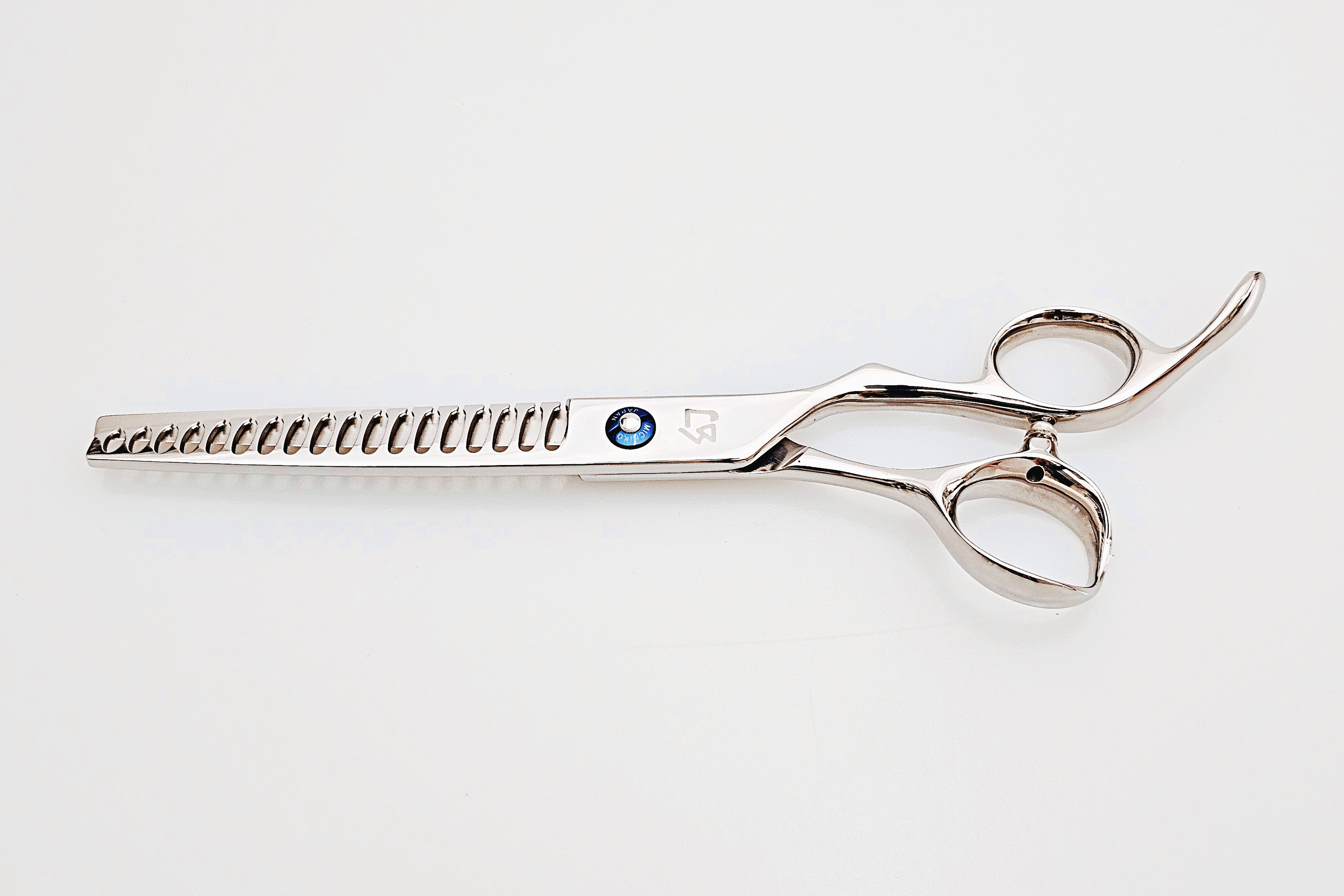 Barber texturizing shears on a white surface.
